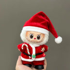 Small plush toy dressed as Santa Claus holding a candy cane against a plain background