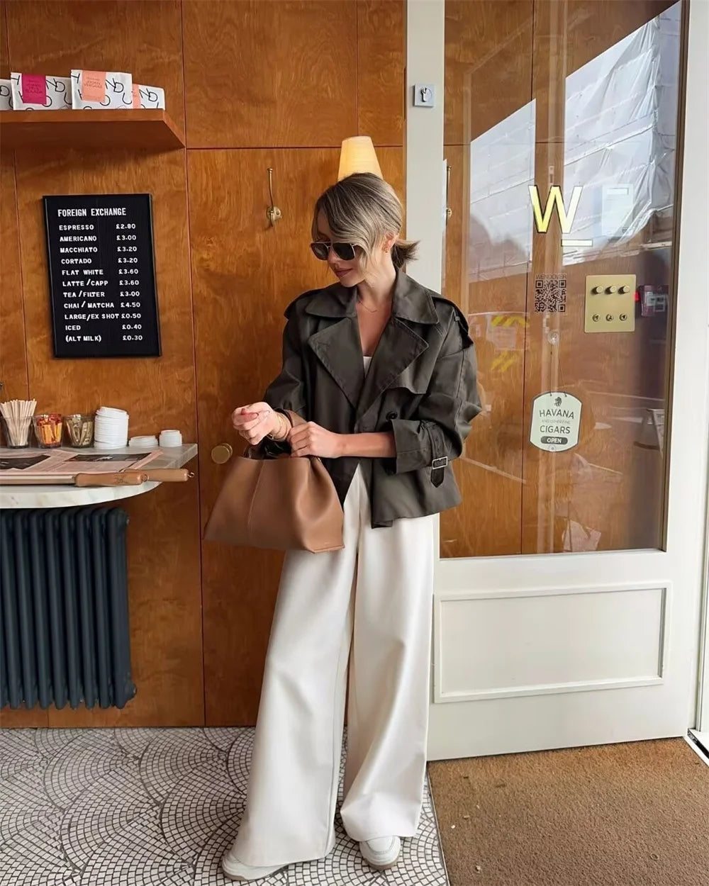 Woman in a stylish outfit standing outside a building with a 'W' logo.