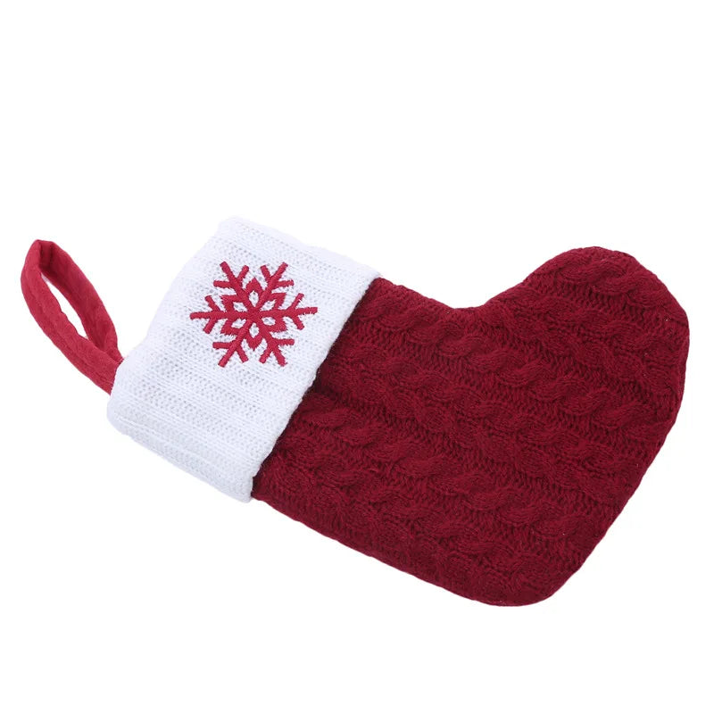 Red knitted dog toy shaped like a mitt with a white cuff and red snowflake design on a white background.