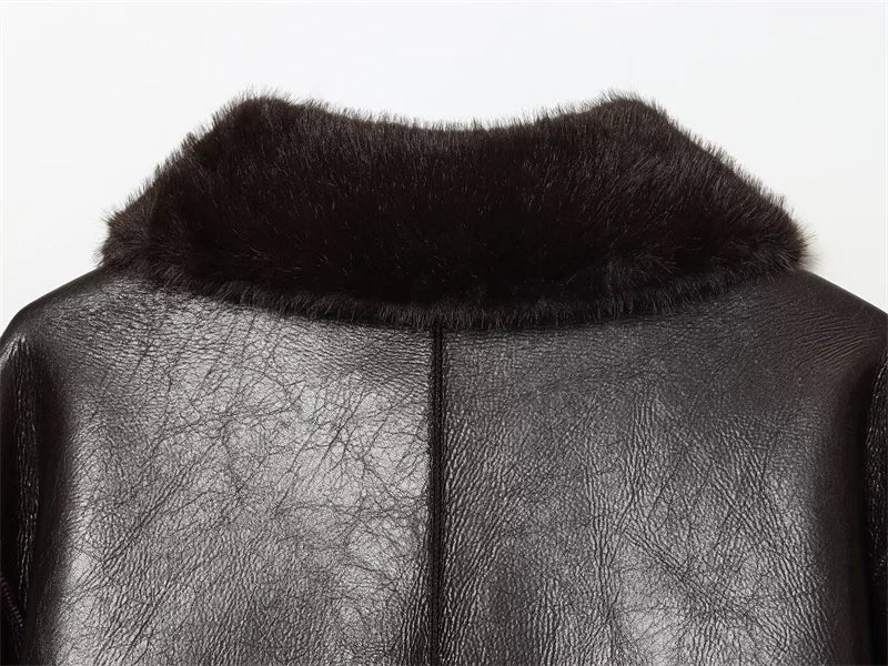 Close-up of a black leather garment with fur collar on a white background