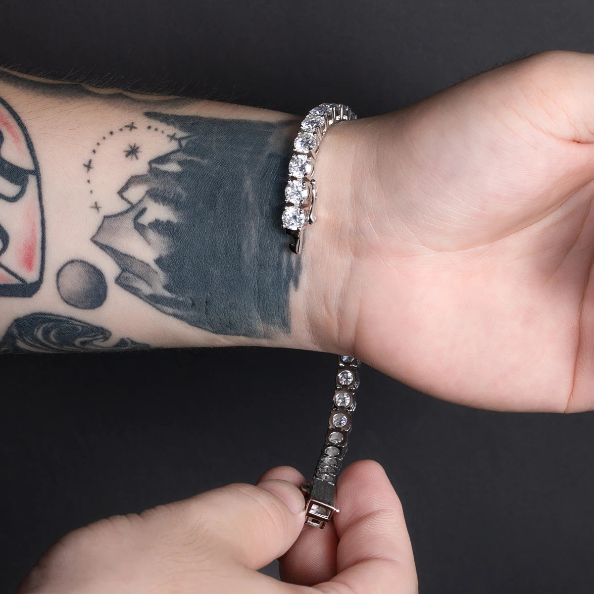 Person wearing a silver bracelet on a dark background