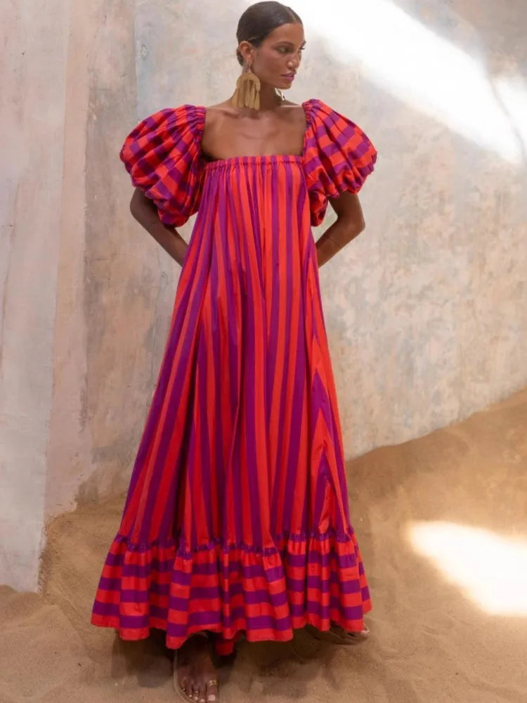 Woman wearing a vibrant red and purple dress with puffed sleeves against a neutral background