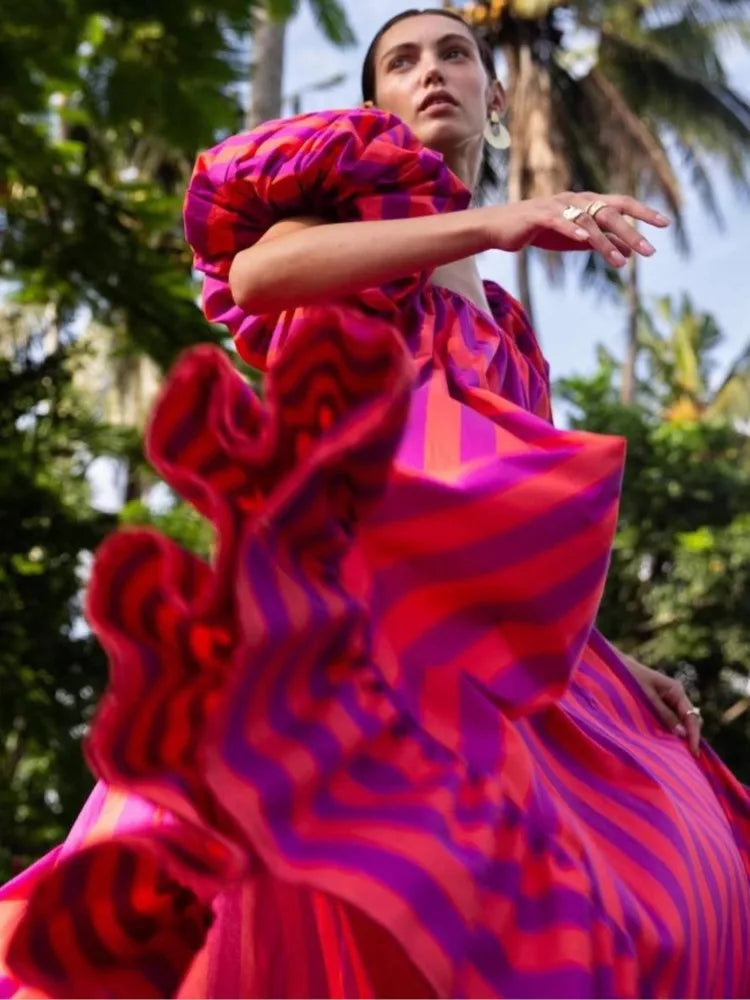 Woman wearing a vibrant pink and red dress with a tropical background