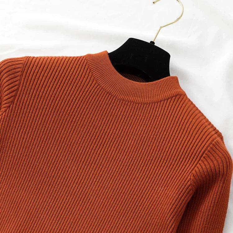 Orange sweater on a hanger against a white background