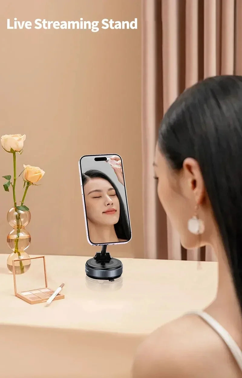 Woman using a live streaming stand with a phone on a table, with a vase of flowers and a pen in the background.