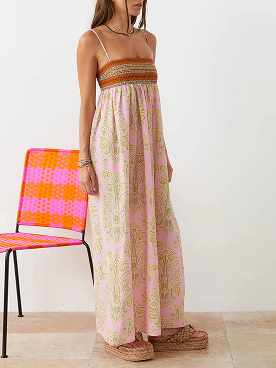Woman wearing a pink and gold patterned dress standing next to a colorful chair.