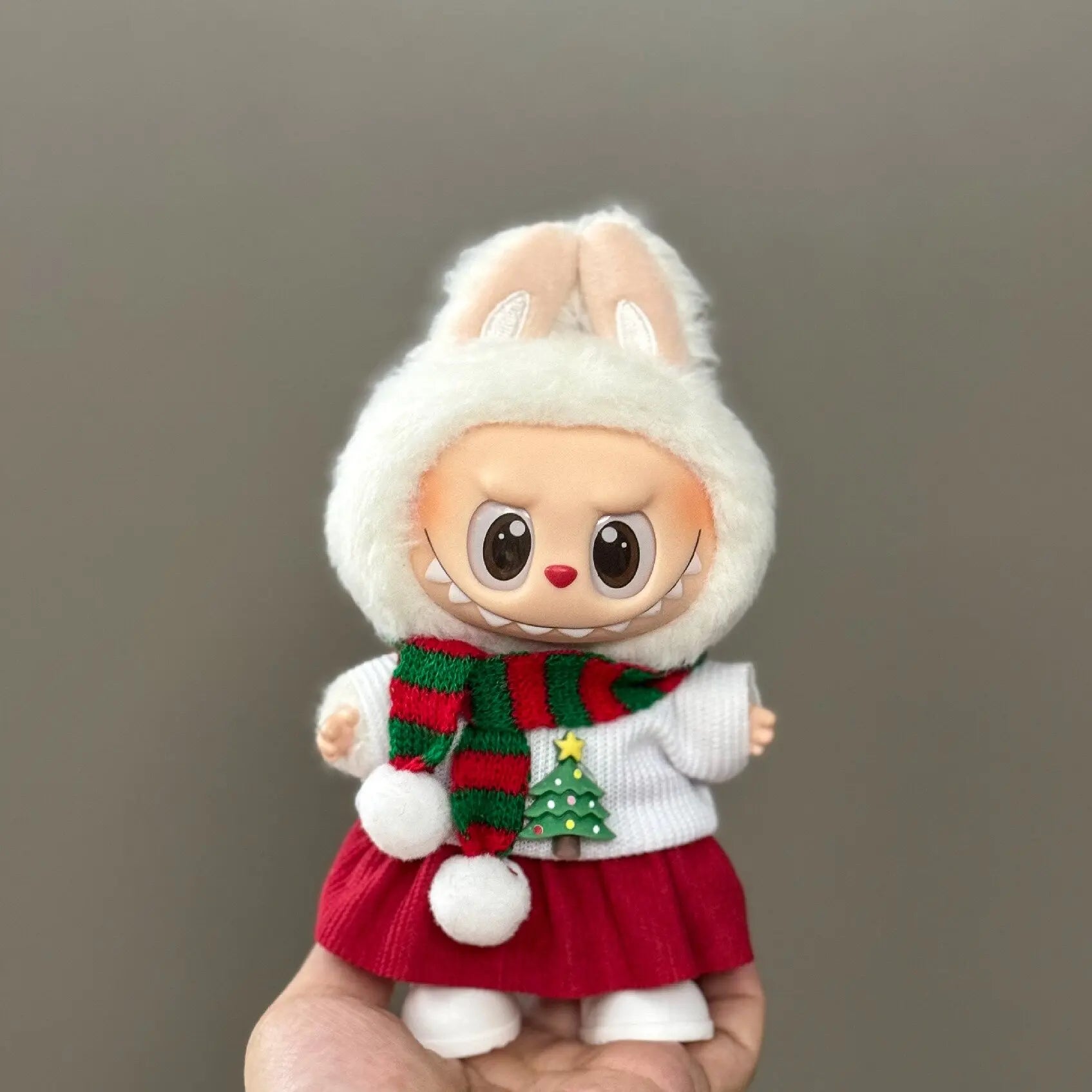 Toy figure of a character wearing a festive outfit with a white hat, red skirt, and green scarf.